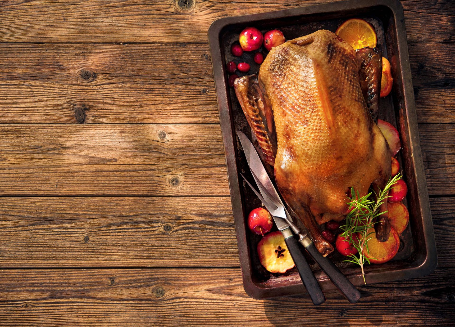 Christmas roast duck with apples and oranges on baking tray